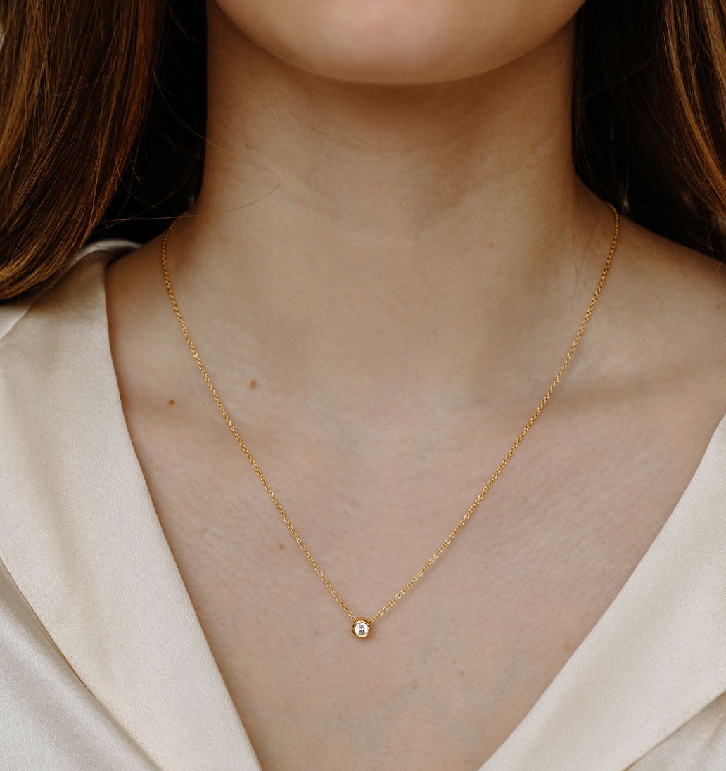 model with brown hair wearing 14k gold with white topaz necklace