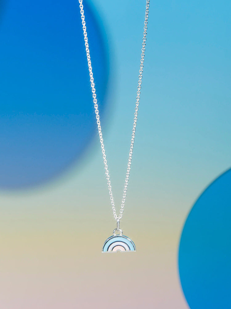 a sterling silver pendant necklace with three colors of mother of pearl, pink, purple, and blue displayed against a background with blue and very light and muted rainbow hues